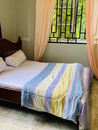 a bed in a bedroom with a window and a bedskirtspectspectspects at Tulivu Nyumba in Arusha