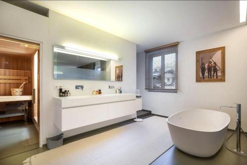 a white bathroom with a tub and a sink at MountainRelaxKtzh in Kitzbühel