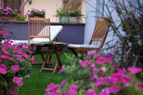 2 sillas y una mesa en un jardín con flores rosas en A l'étoile d'or, en Batzendorf