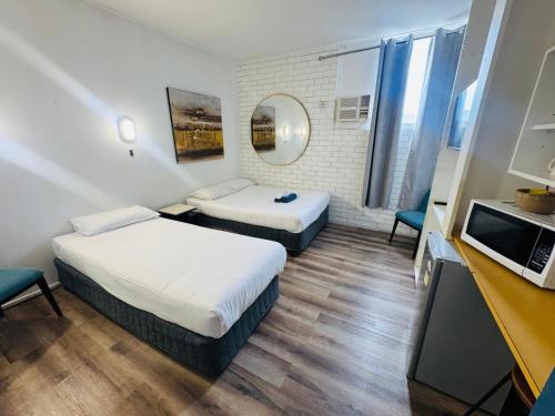 a hotel room with two beds and a mirror at Mayfield Motel in Mayfield