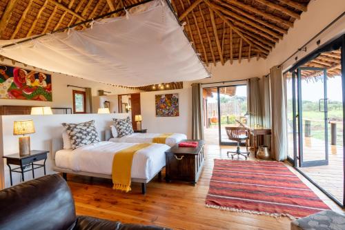 a bedroom with a bed and a living room at Tawi Lodge in Amboseli