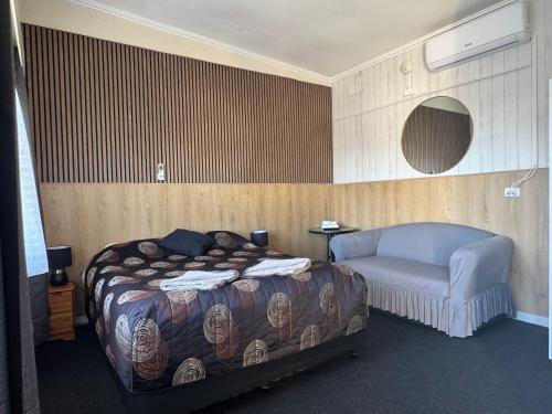 a bedroom with a bed and a couch in it at Blue Lake Motel in Mount Gambier