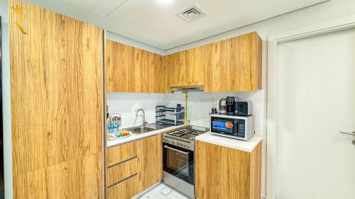 a small kitchen with wooden cabinets and a microwave at Chic Modern 1BR - Executive Al Maryah Stay in Abu Dhabi