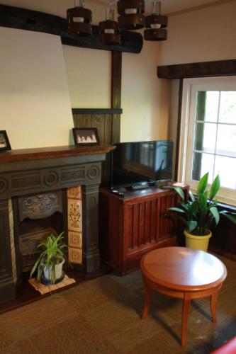a living room with a fireplace and a table at Guest House Dohei in Kamakura