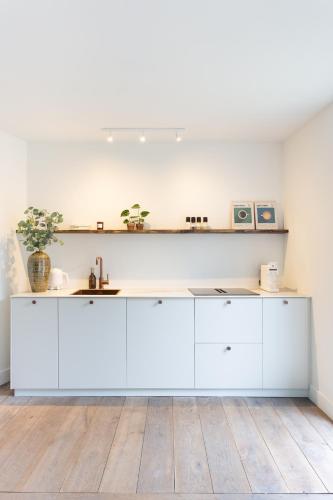 a kitchen with white cabinets and a wooden floor at De Wilden Ezel in Mol