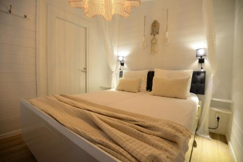 a white bedroom with a bed with a chandelier at Tussen duin en dijk in Warmenhuizen