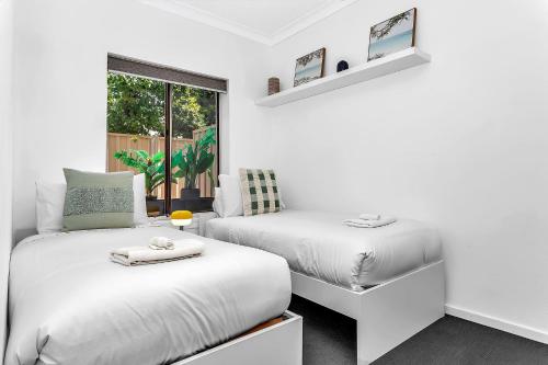 two beds in a white room with a window at Secure Suite in Gated Complex, Courtyard, 5 Min CBD in Rose Park