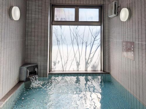 a bathroom with a pool of water with a window at Green Rich Hotel Aso Kumamoto Airport (Artificial hot spring Futamata Yunohana) in Kikuchi