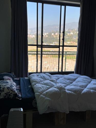 a bed in a room with a large window at Calmsutra retreat in Sānkhu