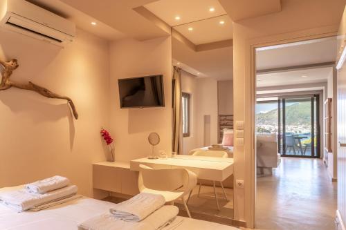 a room with a bed and a table and a television at Core Luxury Suites in Skiathos