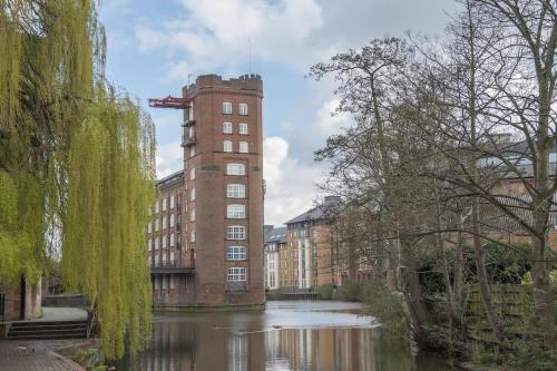 a building with a tower next to a river at ChocoLets - The Quality Suite in York