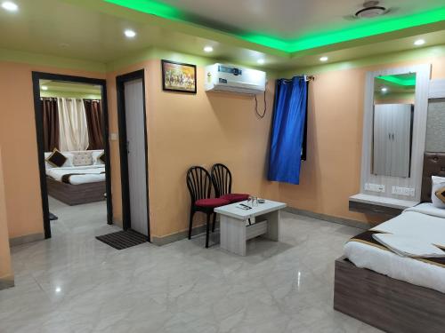 a room with two beds and a table and chairs at Hotel Tara Darshan in Tarapith
