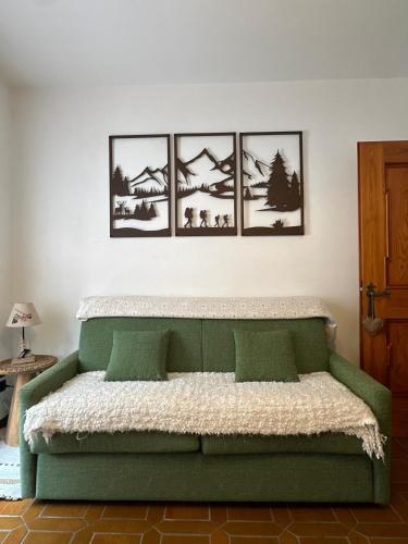 a bedroom with a green bed with four pictures on the wall at Cesira in Mareson