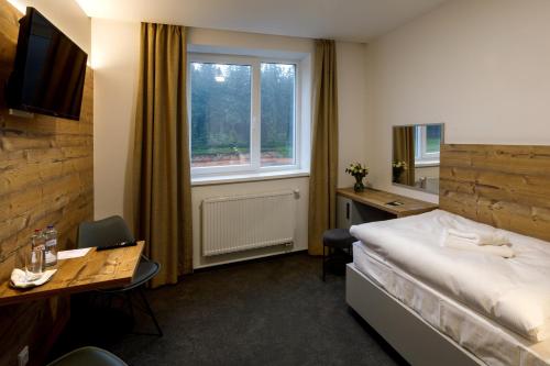 a hotel room with a bed and a desk and a window at Sporthotel Olympia in Stachy