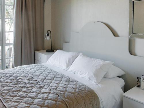 a bedroom with a white bed and a window at Kokerboom House in Vanrhynsdorp