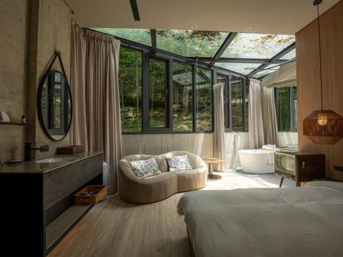 a bedroom with a bed and a bathroom with windows at Deer Chaser Xitou in Lugu Lake