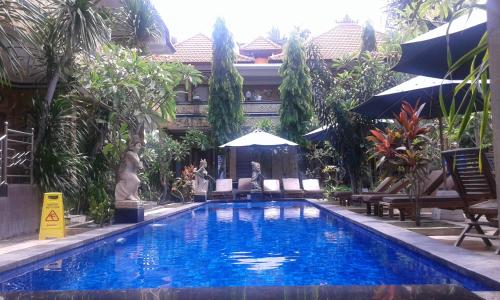 a swimming pool with chairs and umbrellas next to a building at Nitya Home Stay Lembongan in Nusa Lembongan