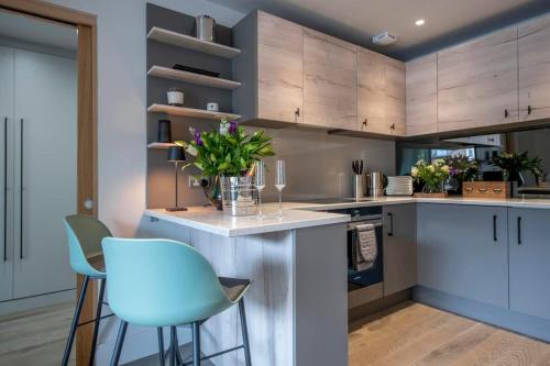 a kitchen with white cabinets and blue chairs at The Quadrant - The Ruskin Suite in York