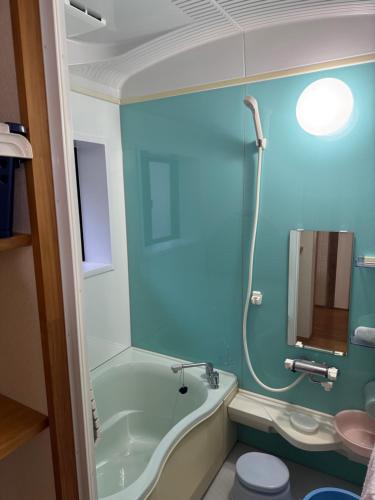 a bathroom with a tub and a toilet and a sink at ぺろんち in Shinkamigoto