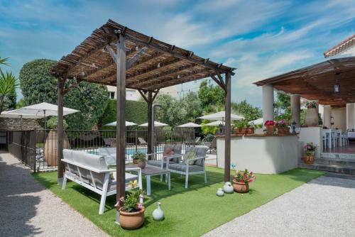 a patio with a table and benches and umbrellas at Hotel Mas Djoliba in Antibes