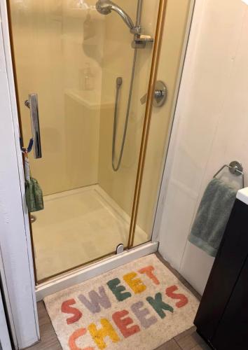 a bathroom with a shower with a rug on the floor at Sunsets on Harbour Kauri or Totara Cabin in Matarangi