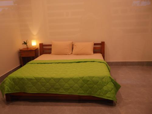 a bed with a green comforter in a room at Green Haven Hill Phu Quoc in Phú Quốc