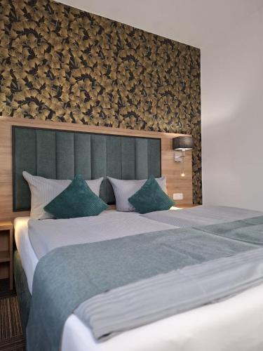 a bedroom with a large bed with a green headboard at Hotel Am Schwarzen Berg in Stade
