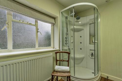 a bathroom with a shower and a chair and a glass shower at Finest Retreats - Dolhyfryd Lodge in Denbigh