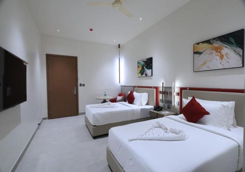 a hotel room with two beds and a television at Antra Luxe in Anumalkudūru