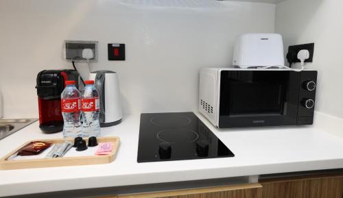 a kitchen counter with a microwave and soda bottles at Al Maryah Studio near Cleveland and Galleria Mall by Central Stay in Abu Dhabi