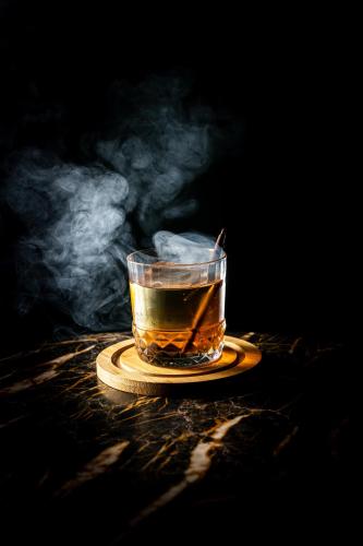 a glass of tea on a plate with smoke at Hotel Gotham Newcastle in Newcastle upon Tyne