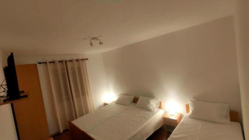 a bedroom with two beds and two lights on the wall at Casa Da Clarinha in Castelo de Paiva