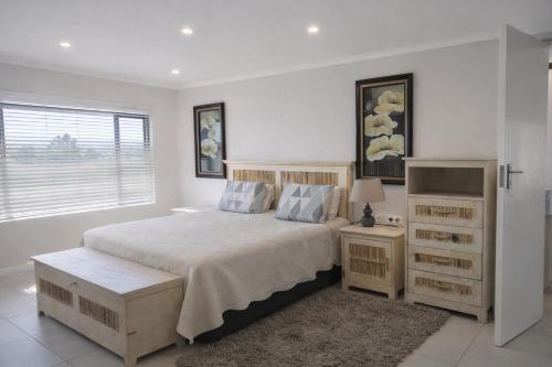 a white bedroom with a bed and a window at Orca View Melkbosstrand in Melkbosstrand