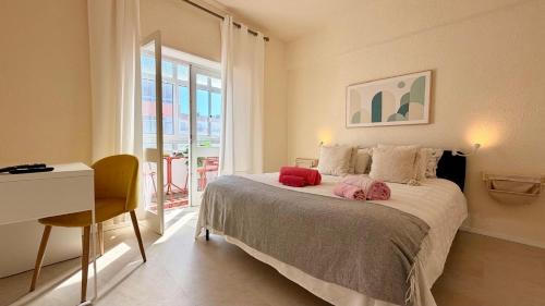 a bedroom with a bed with a desk and a window at Refúgio na Praia de Santa Cruz- A poucos passos da praia, surf e restaurantes in Santa Cruz