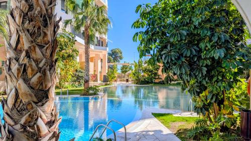 a pool at a resort with palm trees and a building at ALLONBAY sweet apartment in Villajoyosa