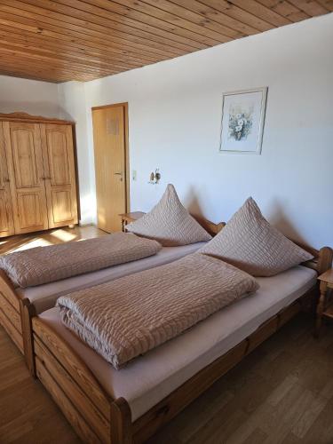 a large bed in a bedroom with a wooden ceiling at Pension Haus Donaublick in Deggendorf