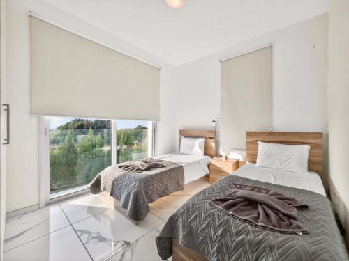 two beds in a room with a window at Alassia Blue Villa in Protaras