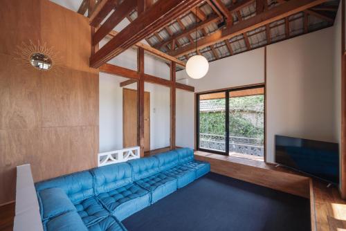 a living room with a blue couch and a tv at TaaCH Okinawa in Nago