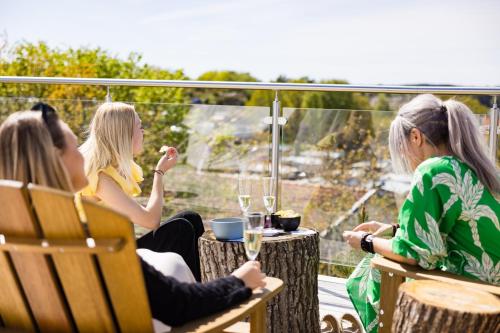 three women sitting around a table on a balcony at GrebbestadFjorden glampingpoddar in Grebbestad