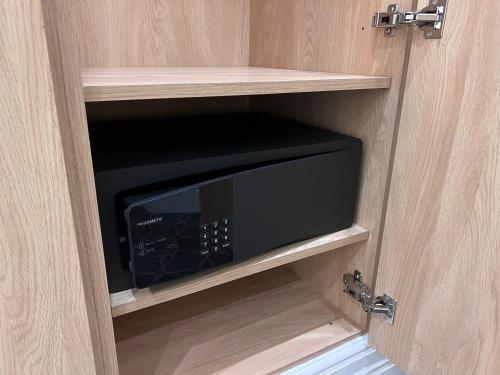 a microwave inside of a cupboard with a door at The Suites - St Pancras Hotel Group in London
