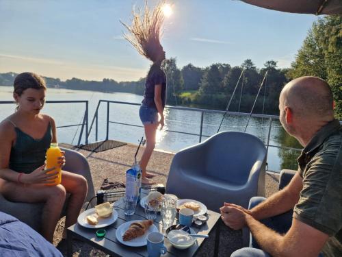 a group of people sitting around a table on a boat at Houseboats Mookerplas met dakterras in Middelaar