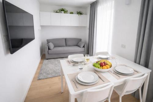 a white dining room table with a bowl of fruit on it at Bormio7 con parcheggio, pista ciclabile, vicino piste sci e terme in Valdisotto