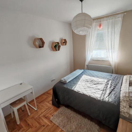 a bedroom with a bed and a desk and a window at Krstić_lux apartman in Subotica
