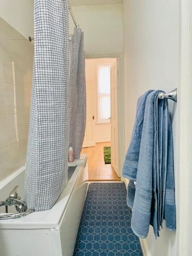 a bathroom with a tub and a shower with blue towels at Cozy Cottage in Liverpool