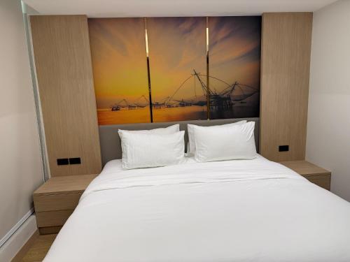 a bedroom with a white bed with a painting on the wall at Viva Hotel Songkhla in Songkhla