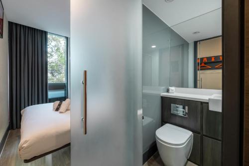 a bathroom with a bed and a sink and a toilet at easyHotel London City Shoreditch in London