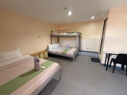 a small room with two beds and a desk at Rain Haven Lodging House in Coron