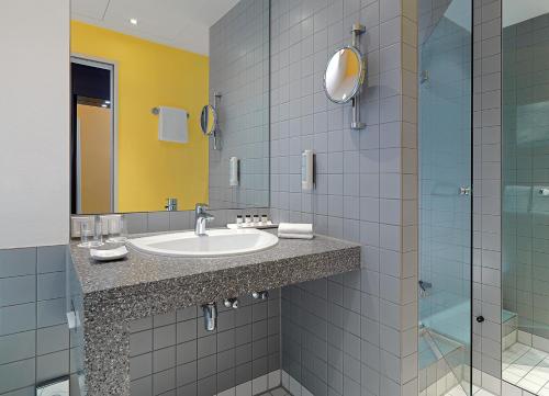 a bathroom with a sink and a glass shower at Sheraton Hannover Pelikan Hotel in Hannover