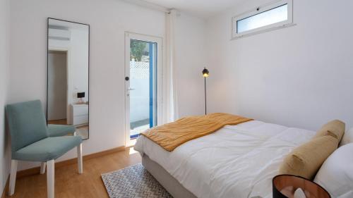 a bedroom with a bed and a chair and a window at Villa Marie e Villa Marieke Ferragudo by Rosado in Ferragudo