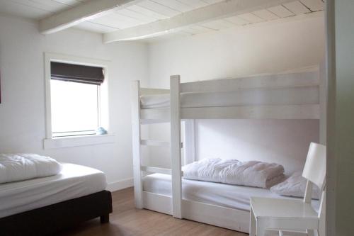 two bunk beds in a white room with a window at De Reggestee in Hellendoorn